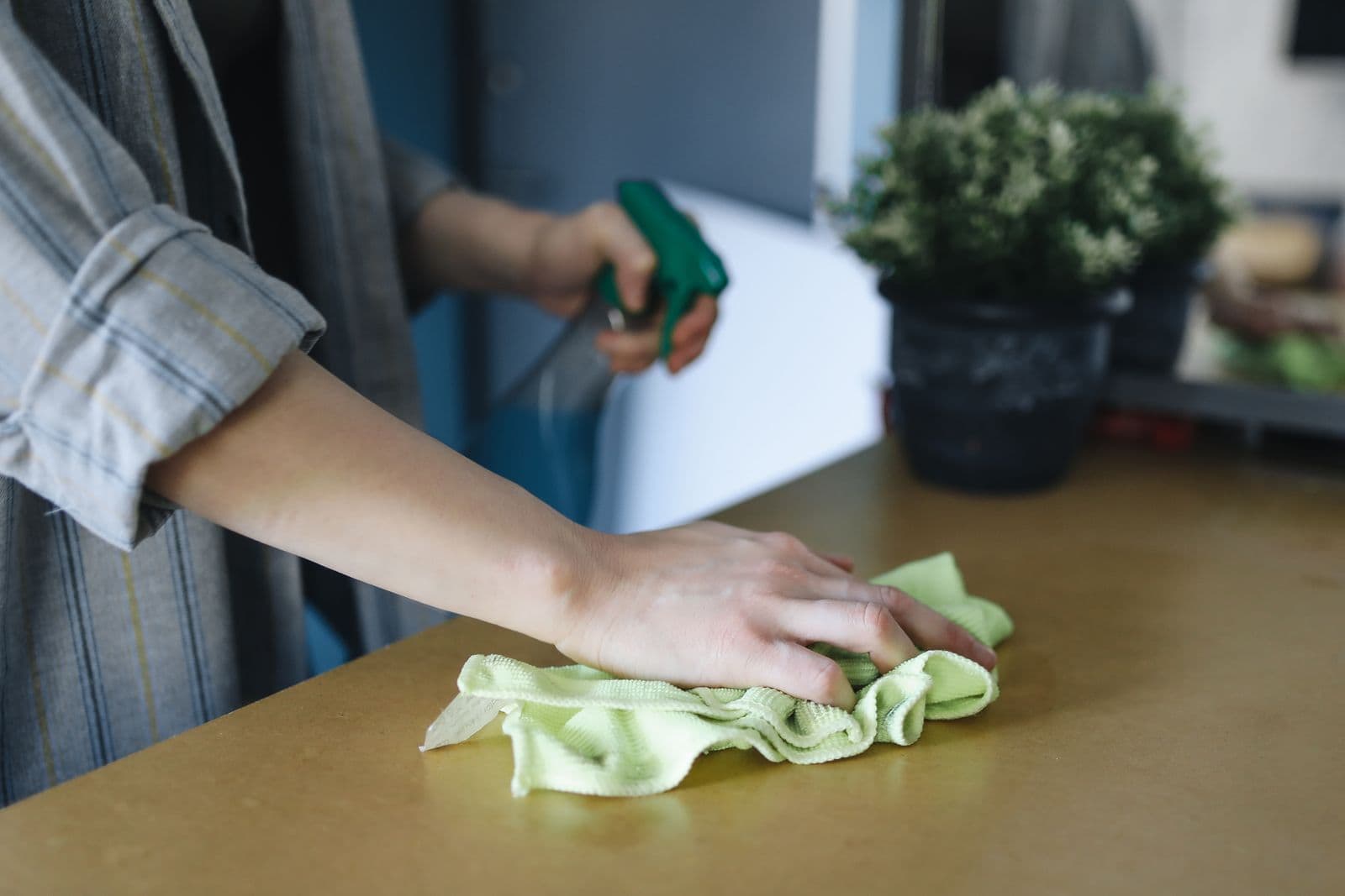 Cleaner wiping a bright kitchen benchtop