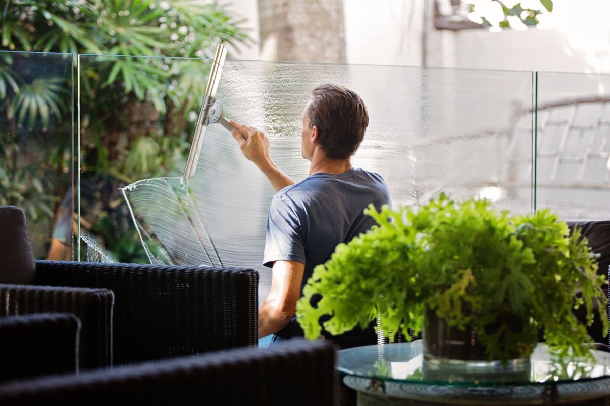 Cleaner finishing a large sunlit window